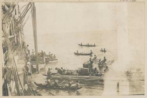 People in boats pulling up to a ship