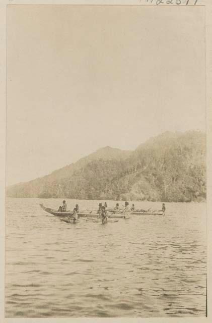 People in boats, shoreline in background