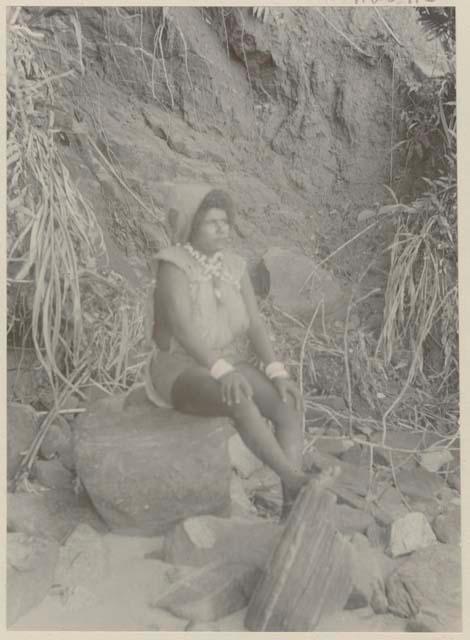 Woman sitting on rock in front of cliff