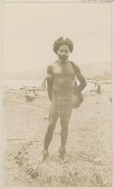 Man standing on the shore, boats in background