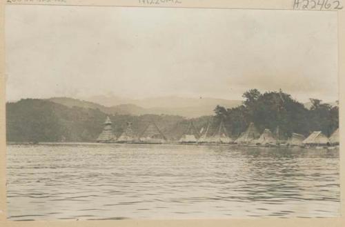 Thatched, pointed pile dwellings along shore