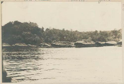 Thatched structures on the shore, possibly pile dwellings