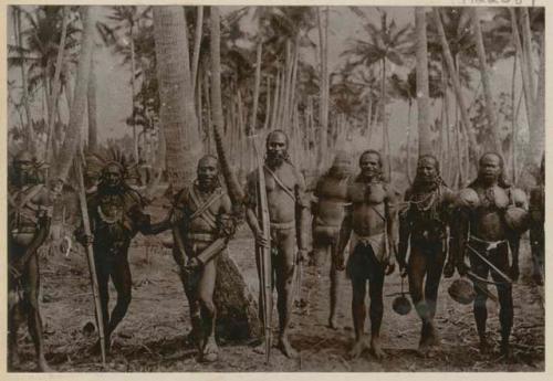 Group of men standing outside with spears and weapons