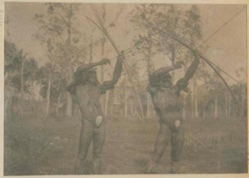 Two men aiming bows and arrows outside