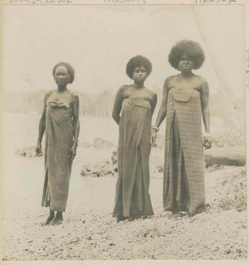 Three women standing in a row on the shore