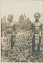 Two men standing outside among vegetation