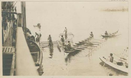 People in boats pulled up to a ship