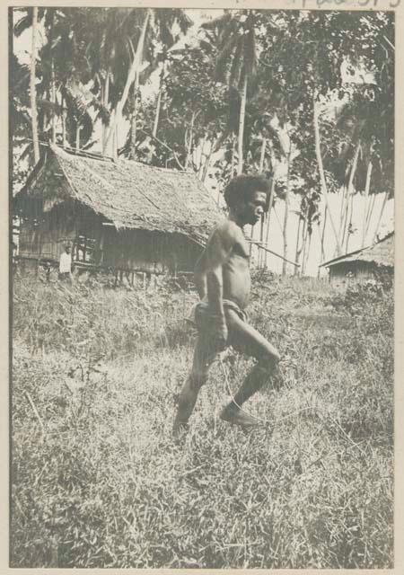 Man walking, trees and structures in background