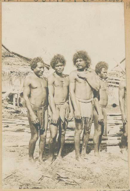 Row of men in front of structures