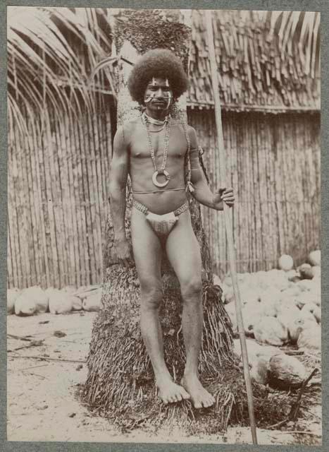 Man with pole in front of tree trunk