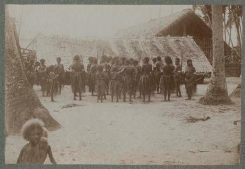 Group facing away from camera, roof made of palm fronds