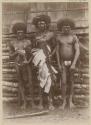 Three men standing outside holding basket and long drums