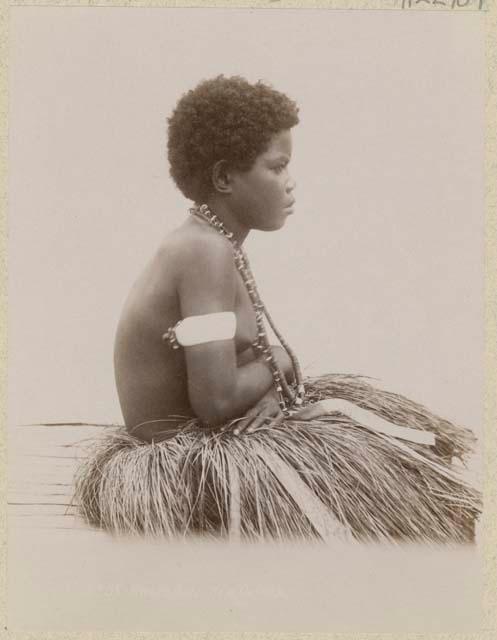 Girl sitting in profile in grass skirt