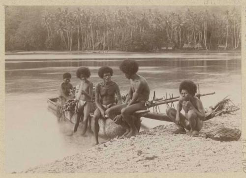 People in outrigger canoe at shore