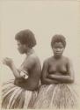 Two women in grass skirts, one in profile