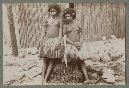 Two women outside in grass skirts