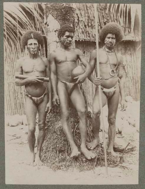 Three men standing outside holding objects