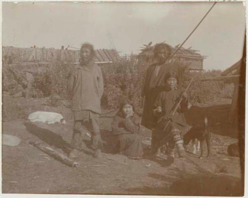 Man with his wives, with dogs and buildings in background