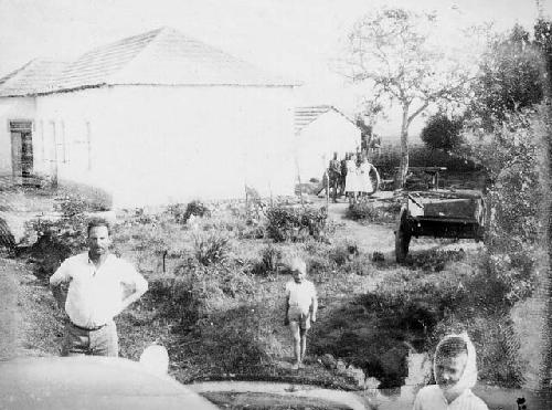 People standing outside a building, with a wagon near them