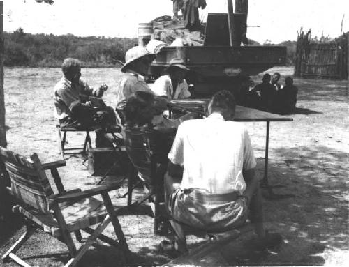 People sitting next to an expedition truck in the camp