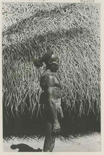 Man standing in front of a hut, side view