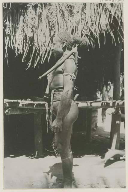 Man standing in front of a hut, side view
