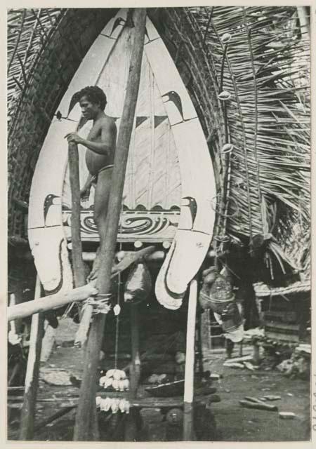 Man standing in front of house with painted decoration and kula shells