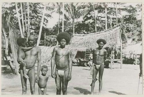 Men and boys standing, houses in background