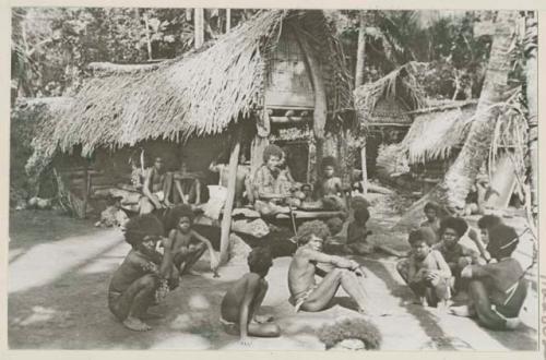 Group of men and boys sitting in front of house