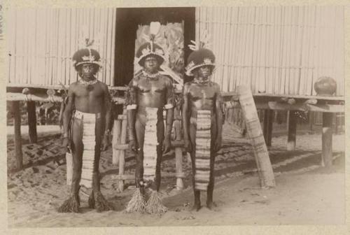 Three men standing in front of a structure