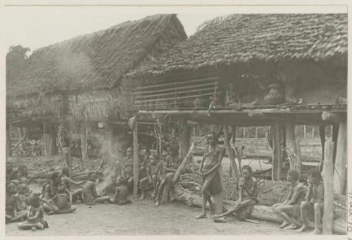 People seated on and around stilted wooden structure with roof but no walls