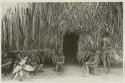 Men and child in front of thatched structure