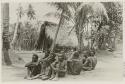 Men and child seated on ground, building in background