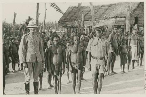 Group standing in front of building, including two men in uniform