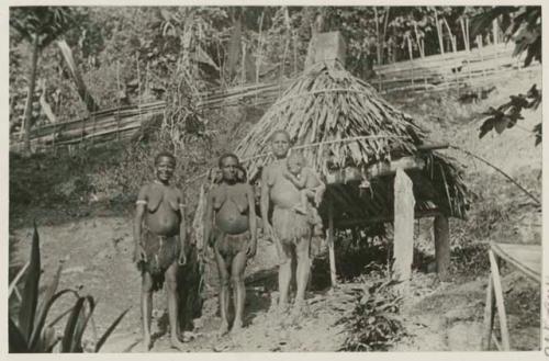 Three wives and nursing child beside burial structure