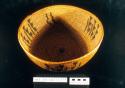 Coiled bowl-shaped basket of willow with Indian head coin button in center base