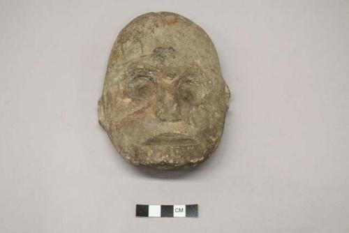 Archaeological ground stone ornament, human effigy face, "H" or "I", "I" carved above right eye.