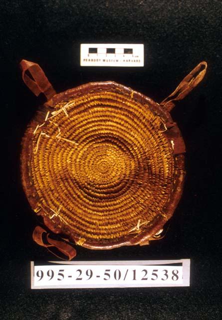 Coiled basketry bowl with leather backing and cowie shell trim