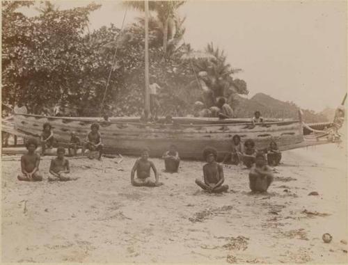 People seated in front of beached boat