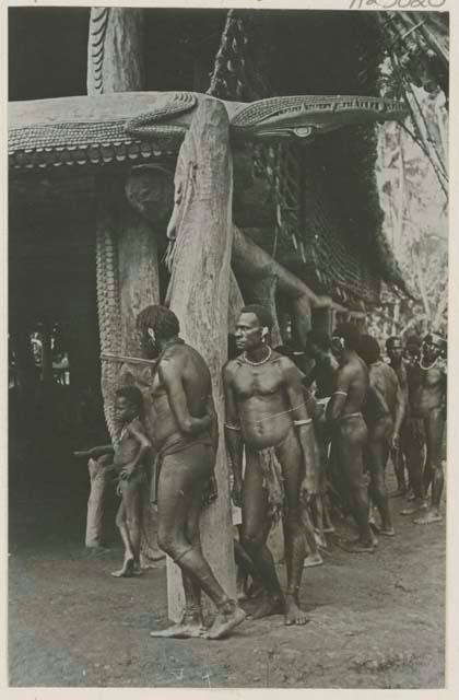 Men beside building with carved crocodile beams