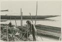 Young man making saksak, canoes in background