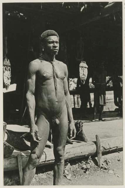 Man in front of structure, mask in background