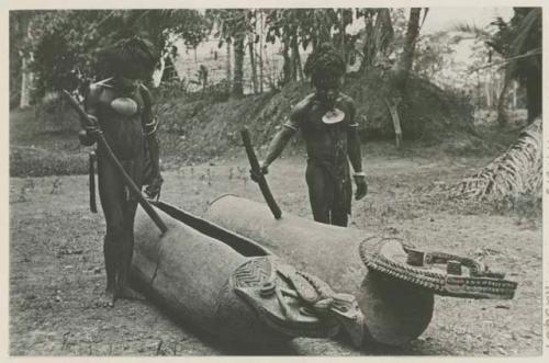 Men beside carved canoes