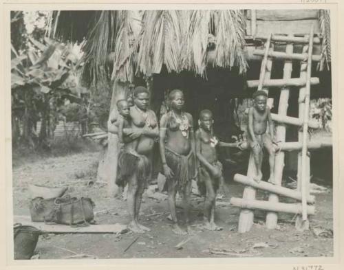 Women and children in front of building on stilts