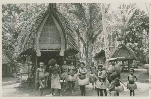 Men, women, and children in front of buildings and trees