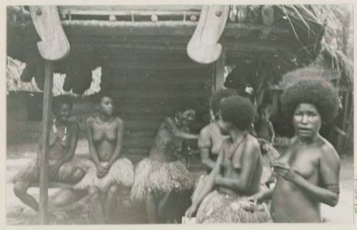 Men, women, and child around small building