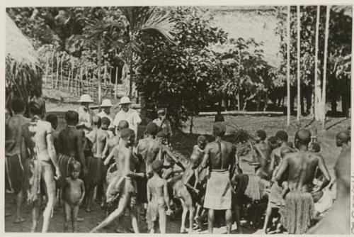 Western men, native police, and group of natives gathered around tobacco