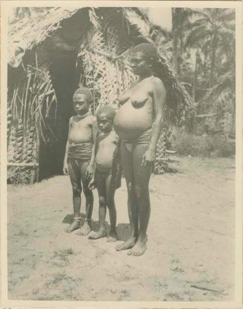 Woman with two children wearing necklaces and girdles made of shell money