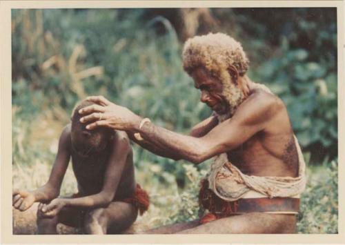 Man delousing his grandson