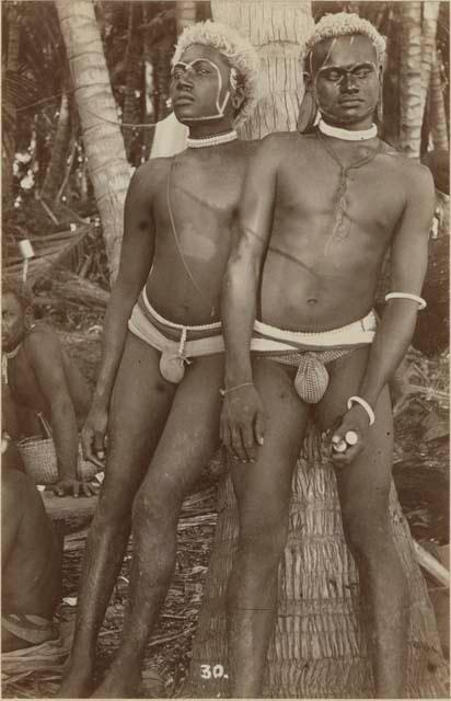 Two men leaning against a tree